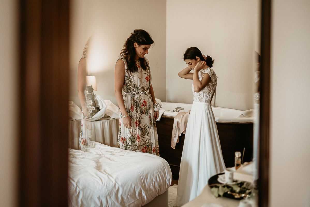 Tenuta La Cascinetta di Buriasco. Matrimonio. Preparazione della sposa. Sposa e testimone riflesse nello specchio.