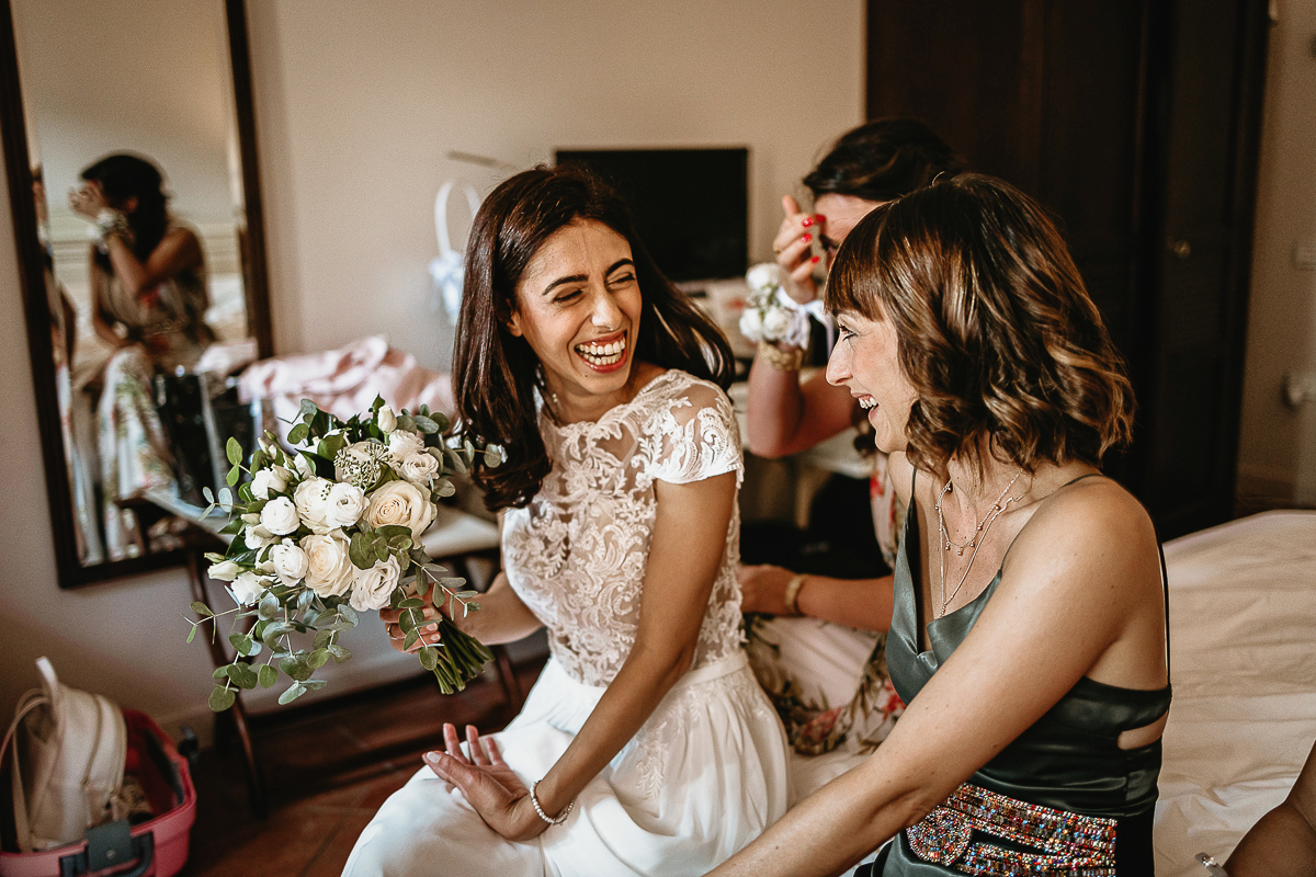 Tenuta La Cascinetta di Buriasco. Matrimonio. Preparazione della sposa. sposa scherza con le amiche.