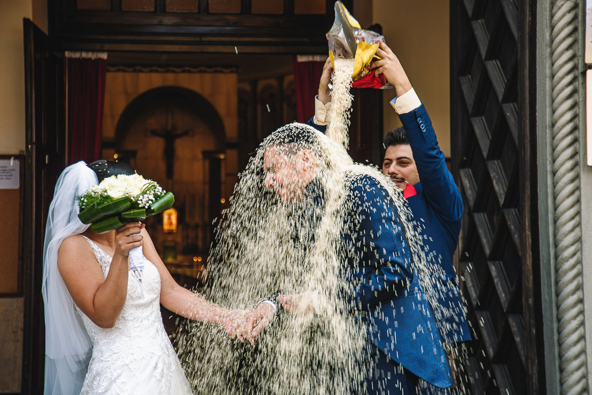 Matrimonio a Torino, chiesa di San Gioacchino. Cerimonia.Uscita degli sposi. Lancio del riso. Amico svuota un intero pacco di riso sulla testa dello sposo.