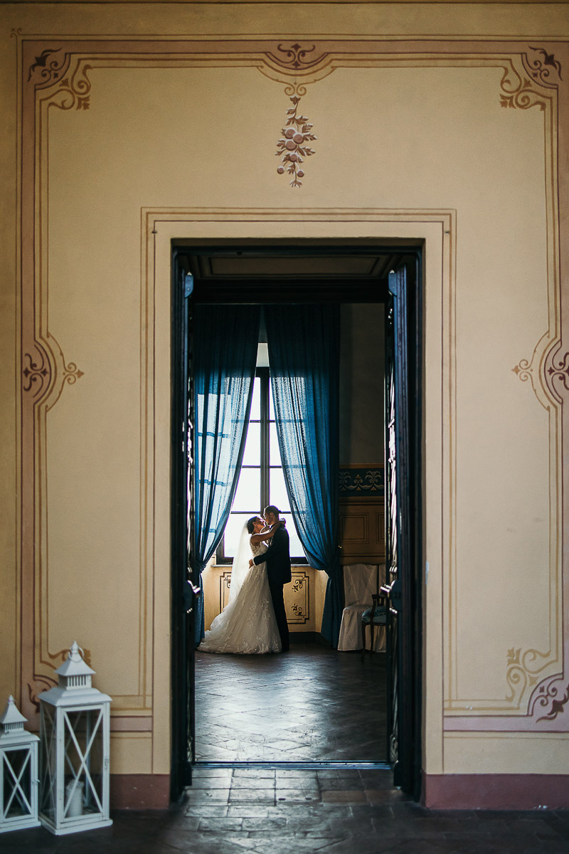 Castello di Cortanze, matrimonio. Ricevimento.Ritratto degli sposi davanti alla finestra. bacio. Ripresi dall'esterno