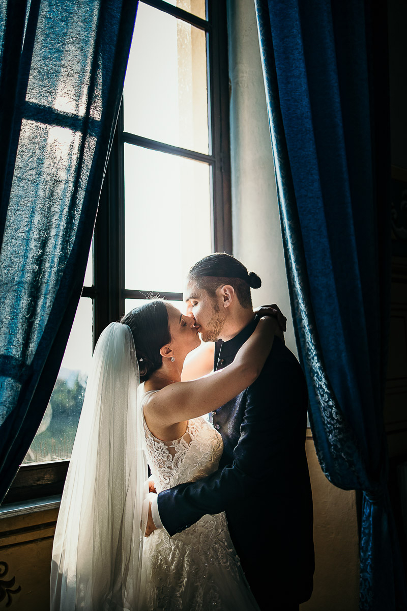Castello di Cortanze, matrimonio. Ricevimento. Bacio degli sposi tra i tendaggi della finestra