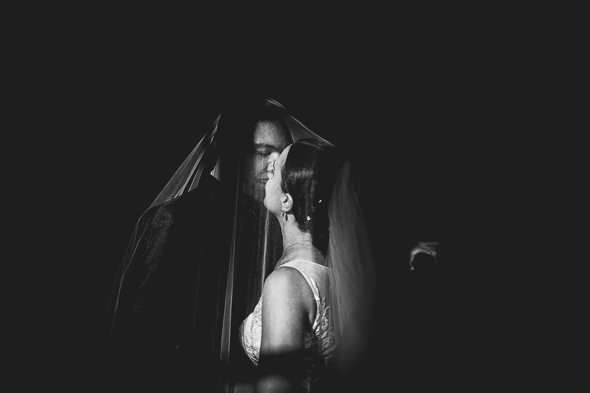 Castello di Cortanze, matrimonio. Ricevimento.Ritratto degli sposi sotto il velo. Luce drammatica. Bianco e nero.