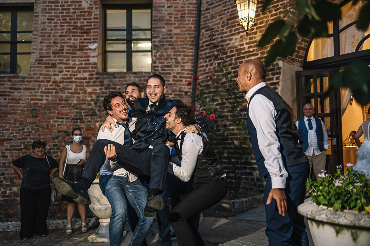 Castello di Cortanze, matrimonio. Ricevimento.Festa. amici sollevano lo sposo.