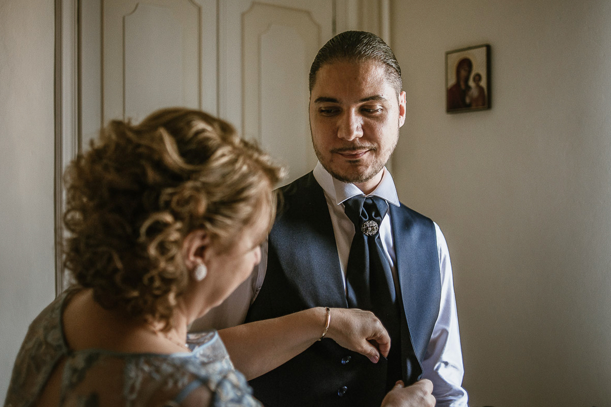 Matrimonio a Torino, preparazione dello sposo.mamma abbottona il gilet dello sposo.