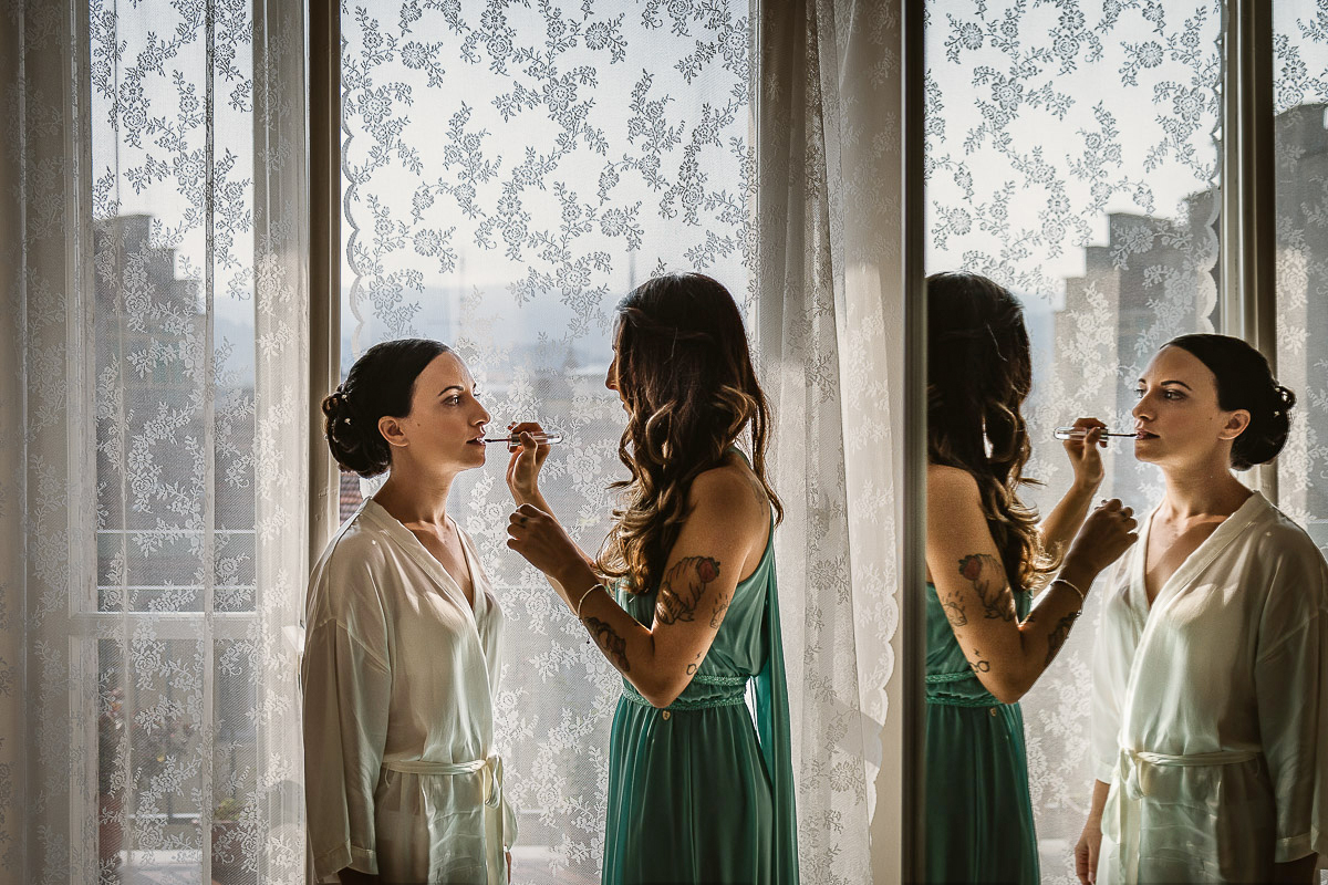 Matrimonio a Torino, preparazione della sposa, ultimo ritocco del make-up davanti alla porta finestra.