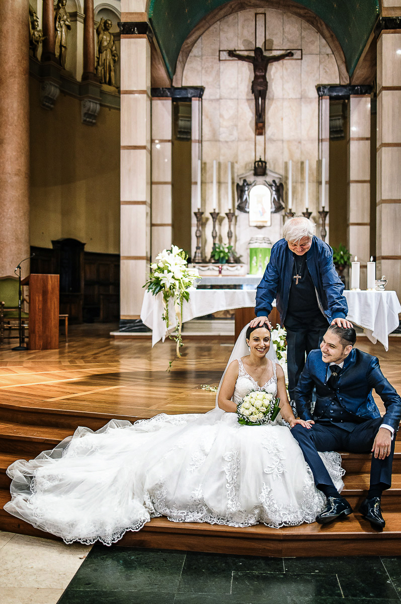 Matrimonio a Torino, chiesa di San Gioacchino. Cerimonia. Sposi seduti sulle scale dell'altare. Prete mette le mani sui loro capi.