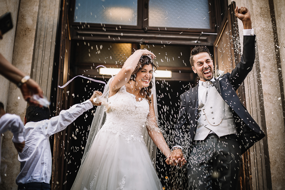 Matrimonio a Torino, cerimonia chiesa dei Santi Angeli Custodi. messa. lancio del riso. Sposo alza il pugno in segno di vittoria.