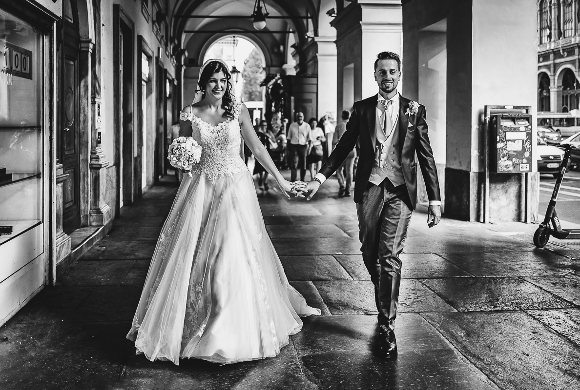 Matrimonio a Torino. Sessione di coppia davanti alla stazione di Porta Nuova. Sposi camminano sotto i portici.