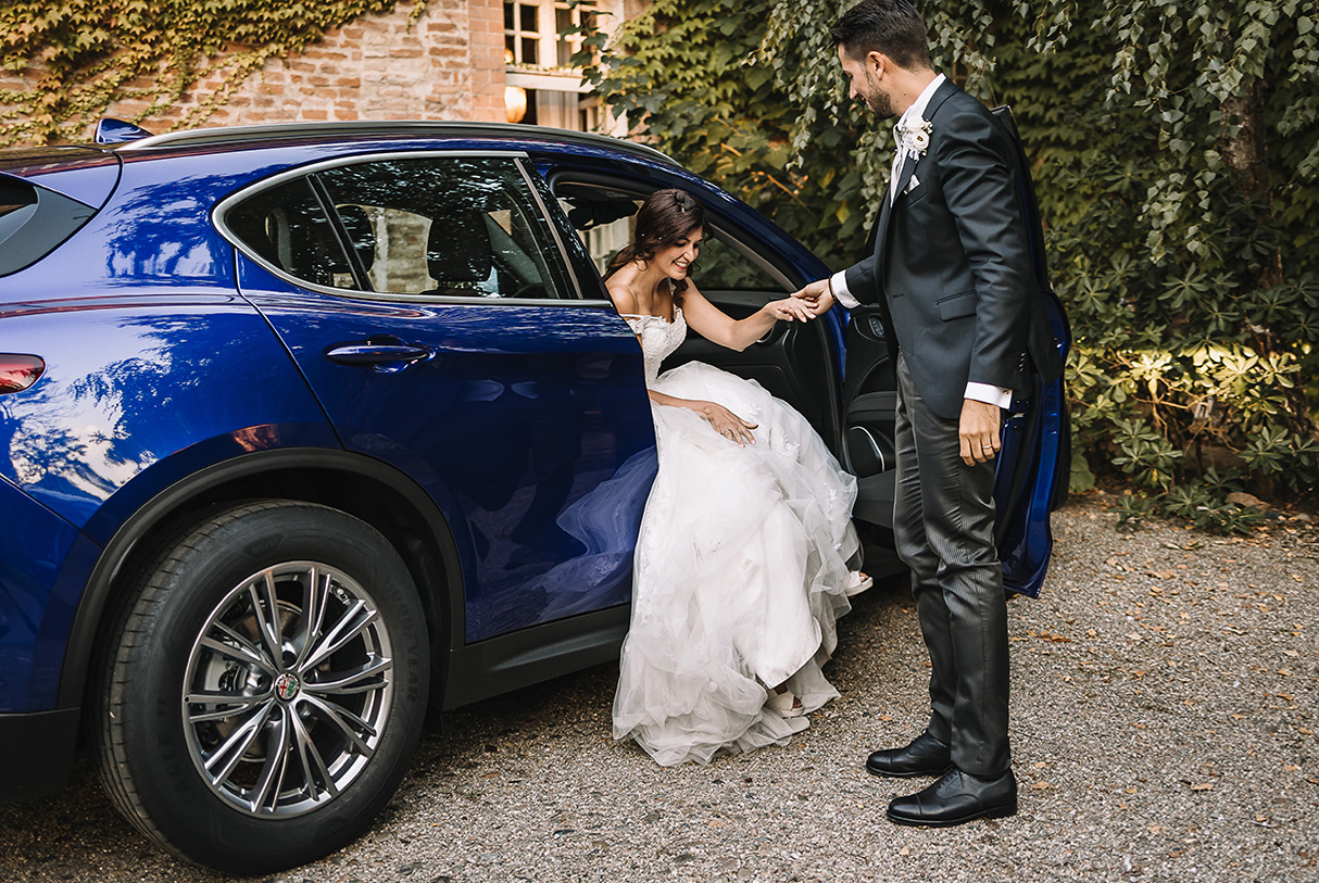 matrimonio al Castello di Oviglio. Ricevimento. Arrivo degli sposi. Sposo aiuta la sposa ad uscire dall'auto