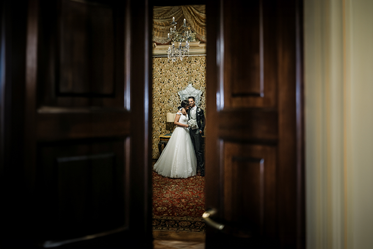 matrimonio al Castello di Oviglio. Cena. Sposiaspettano di entrare in sala. Fotografati dalla porta socchiusa.