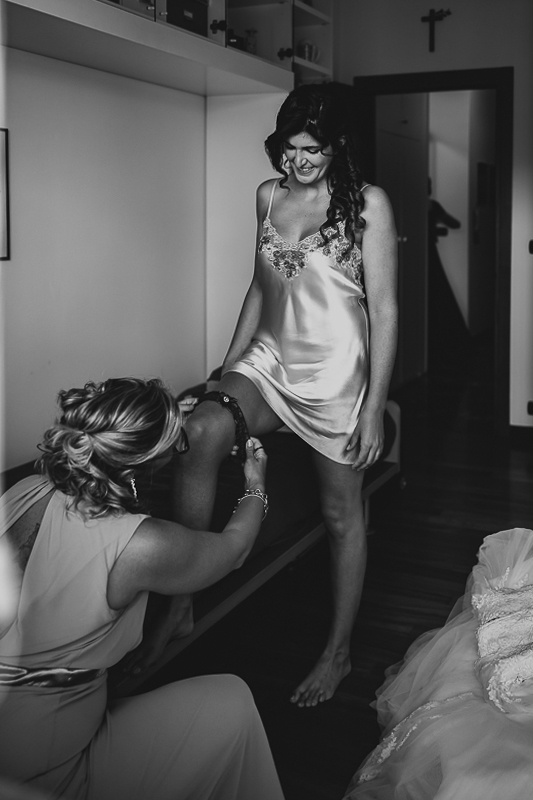 Matrimonio a Torino, preparazione della sposa.Amica mette la giarrettiera alla sposa.