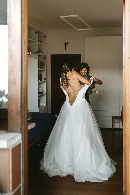 Matrimonio a Torino, preparazione della sposa. Mamma aiuta la sposa ad indossare l'abito.