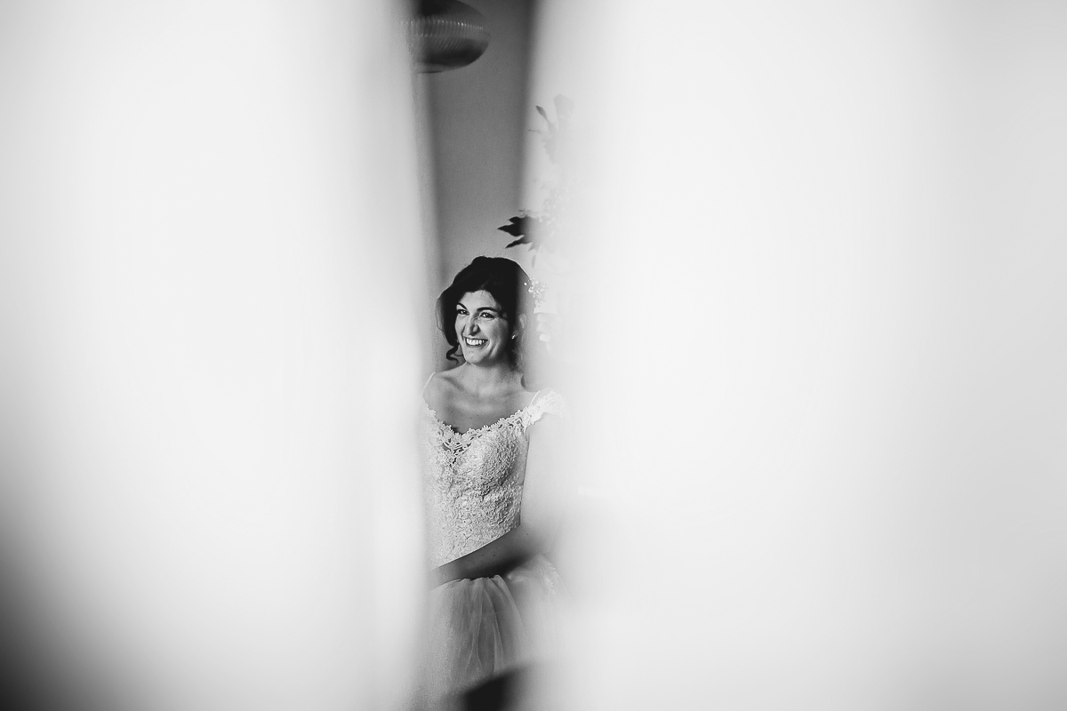 Matrimonio a Torino, preparazione della sposa. Sposa ripresa tra i tendaggi.