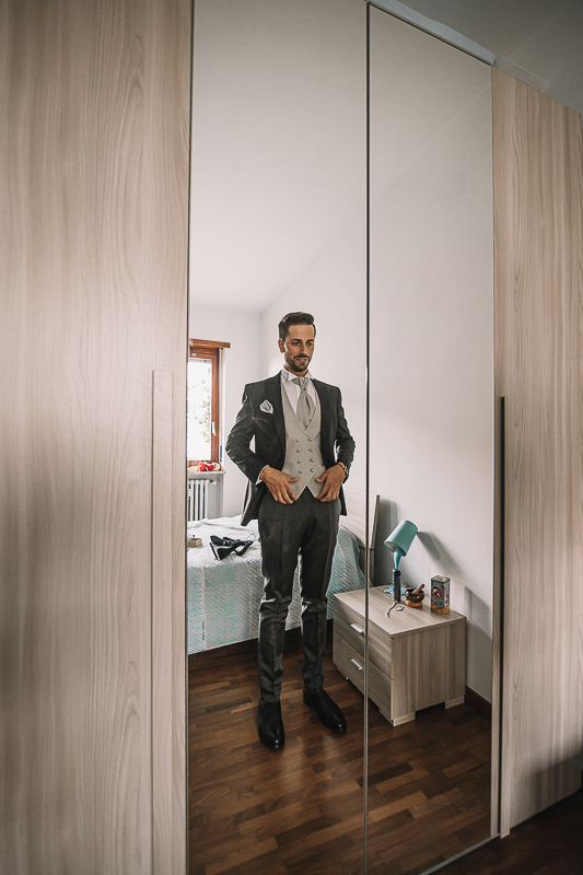 Matrimonio a Torino, preparazione dello sposo. Sposo vestito si guarda nello specchio.
