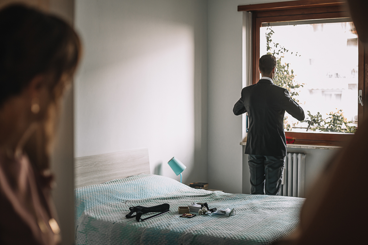 Matrimonio a Torino, preparazione dello sposo. Sposo si sistema alla finestra. mamma guarda dalla porta.
