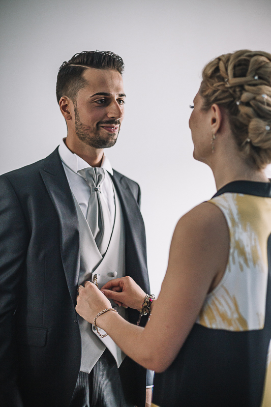 Matrimonio a Torino, preparazione dello sposo. Sorella abbottona il gilet dello sposo.
