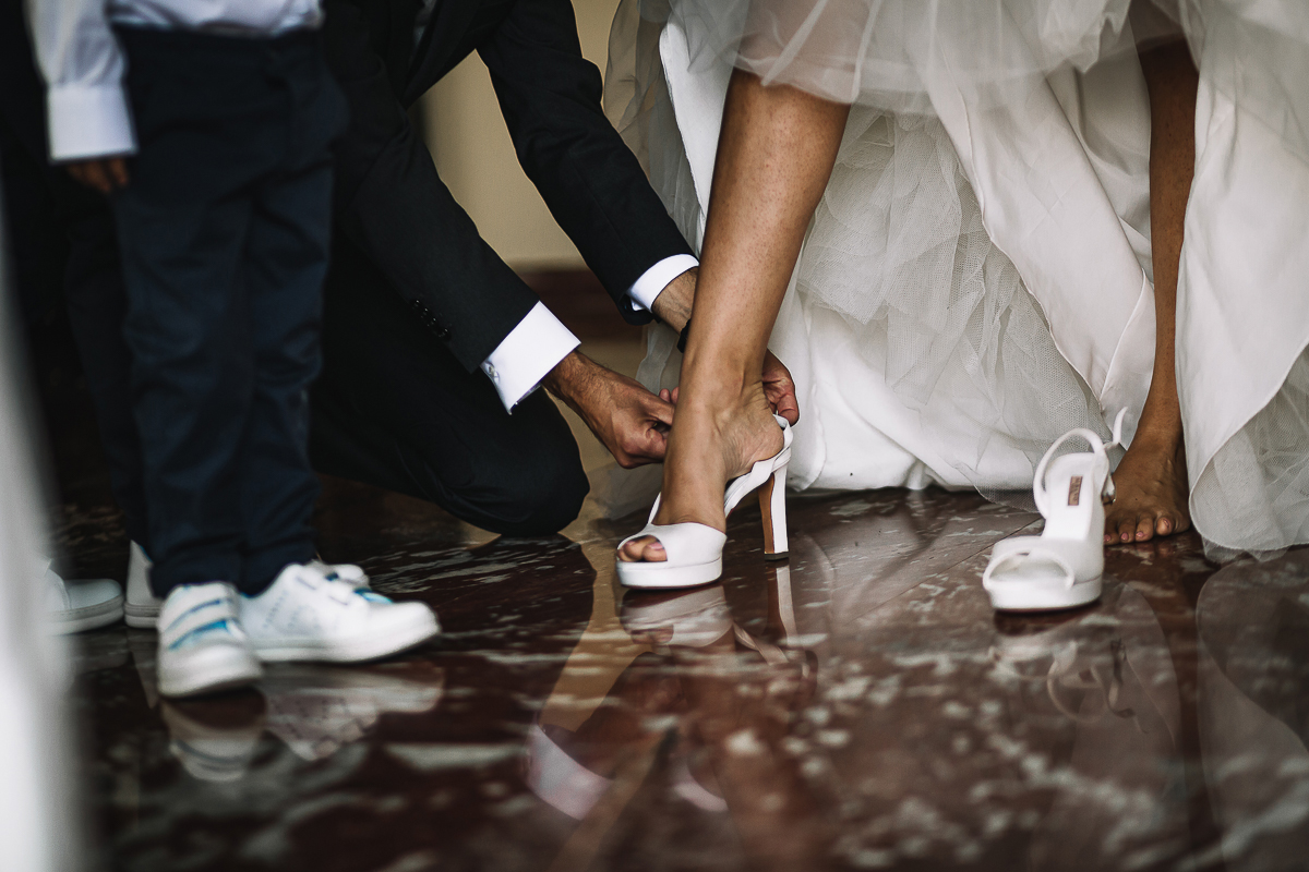 Matrimonio a Torino, preparazione della sposa. Fratello aiuta la sposa a calzare le scarpe. Dettaglio.