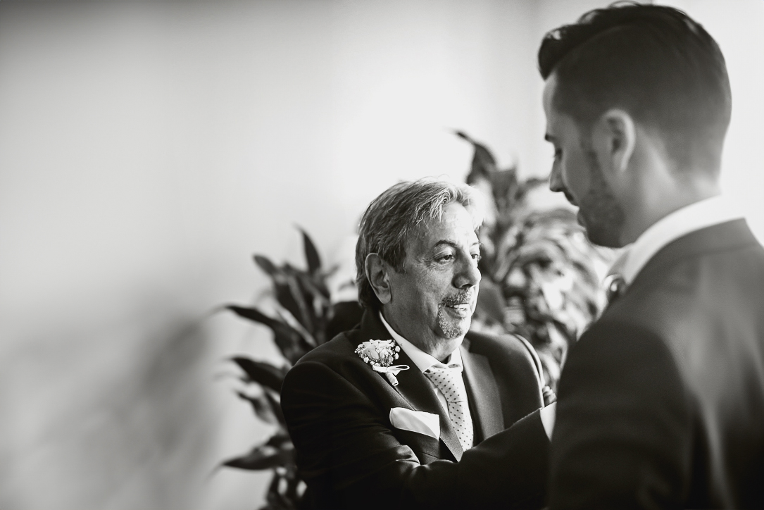 Matrimonio a Torino, preparazione dello sposo. Padre abbottona la giacca dello sposo.