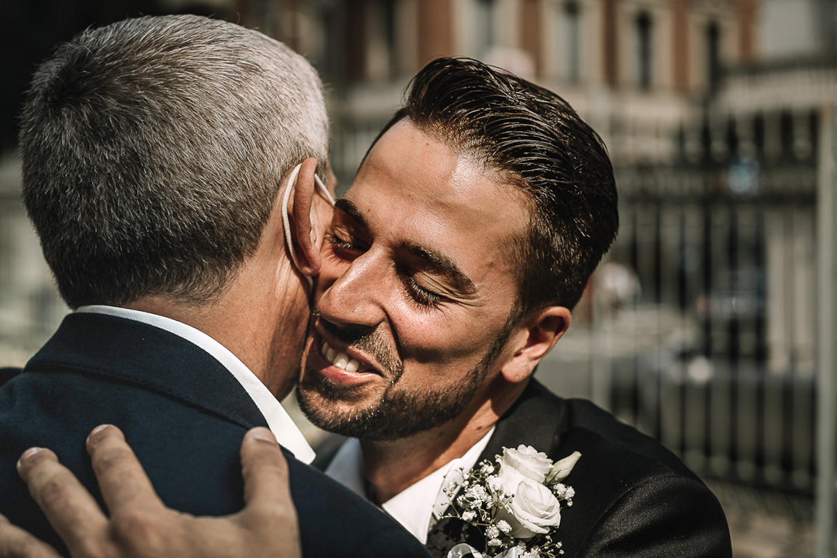 Matrimonio a Torino, cerimonia chiesa dei Santi Angeli Custodi. Sposo abbraccia un invitato.
