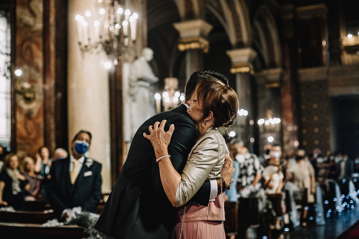 Matrimonio a Torino, cerimonia chiesa dei Santi Angeli Custodi. messa. Sposo abbraccia la mamma all'altare.