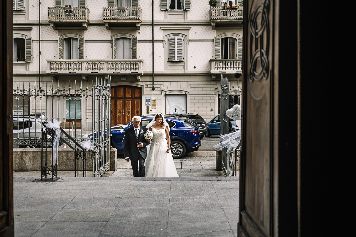 Matrimonio a Torino, cerimonia chiesa dei Santi Angeli Custodi. messa. Sposa sta per entrare in chiesa al braccio del padre.