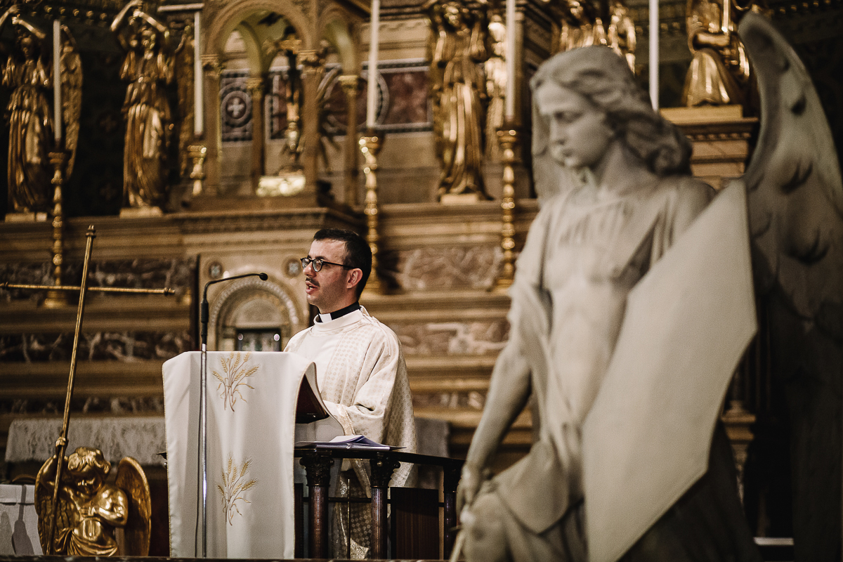 Matrimonio a Torino, cerimonia chiesa dei Santi Angeli Custodi. messa. Giovane sacerdote con una statua di un angelo