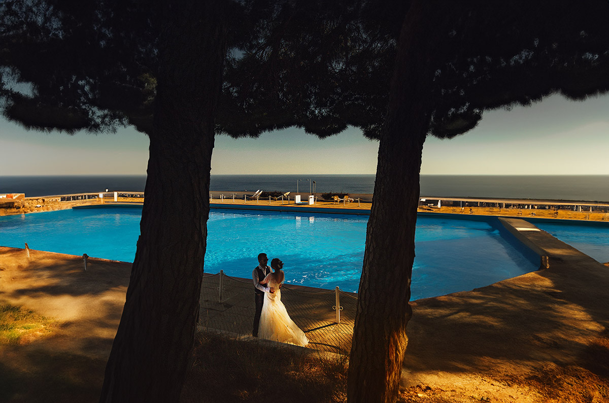 Destination wedding ad Arenzano (GE) presso l'Hotel Punta San Martino.Sposi a bordo piscina, tra due alberi.