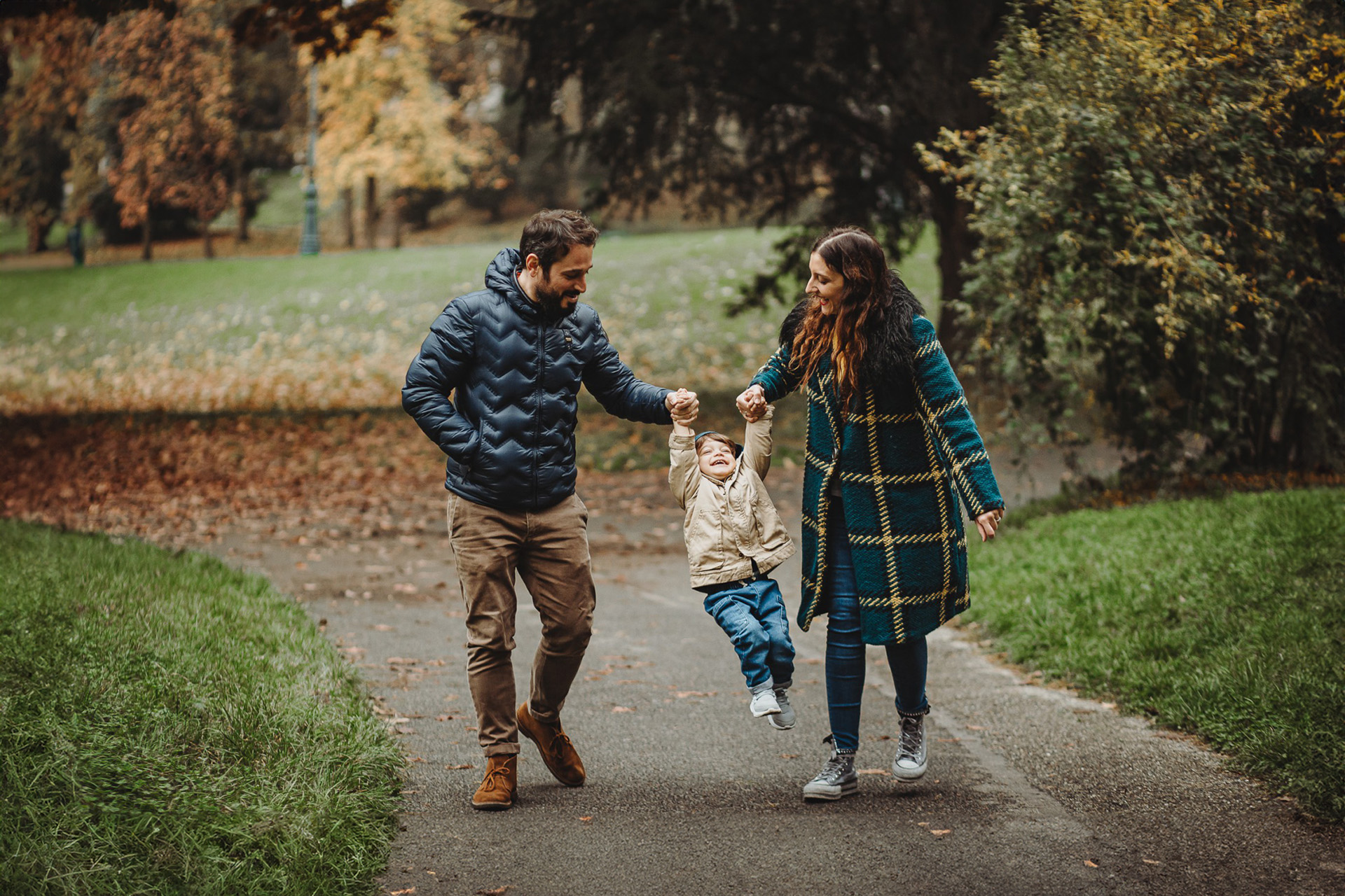 Parco del Valentino, fotografia di famiglia. Sessione fotografica autunnale. Papà e mamma fanno volare il bambino.