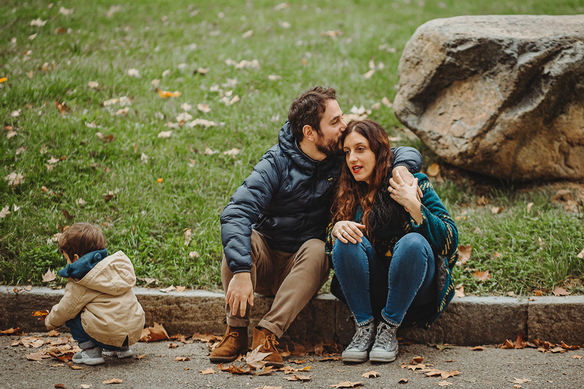 Parco del Valentino, fotografia di famiglia. Sessione fotografica autunnale. Papà bacia la mamma sulla testa. Il bambino gioca.