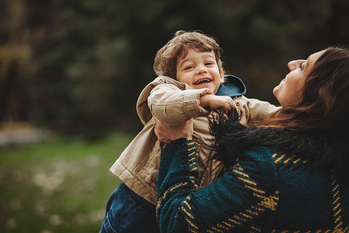 Parco del Valentino, fotografia di famiglia. Sessione fotografica autunnale. Papà e mamma fanno volare il bambino di fronte a loro.
