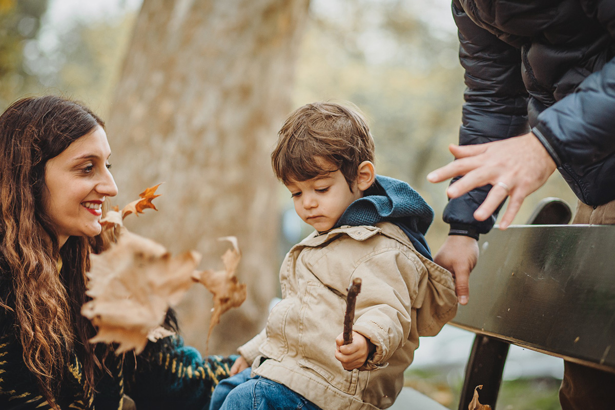 Parco del Valentino, fotografia di famiglia. Sessione fotografica autunnale. Papà mamma e bambino giocano con le foglie autunnali.