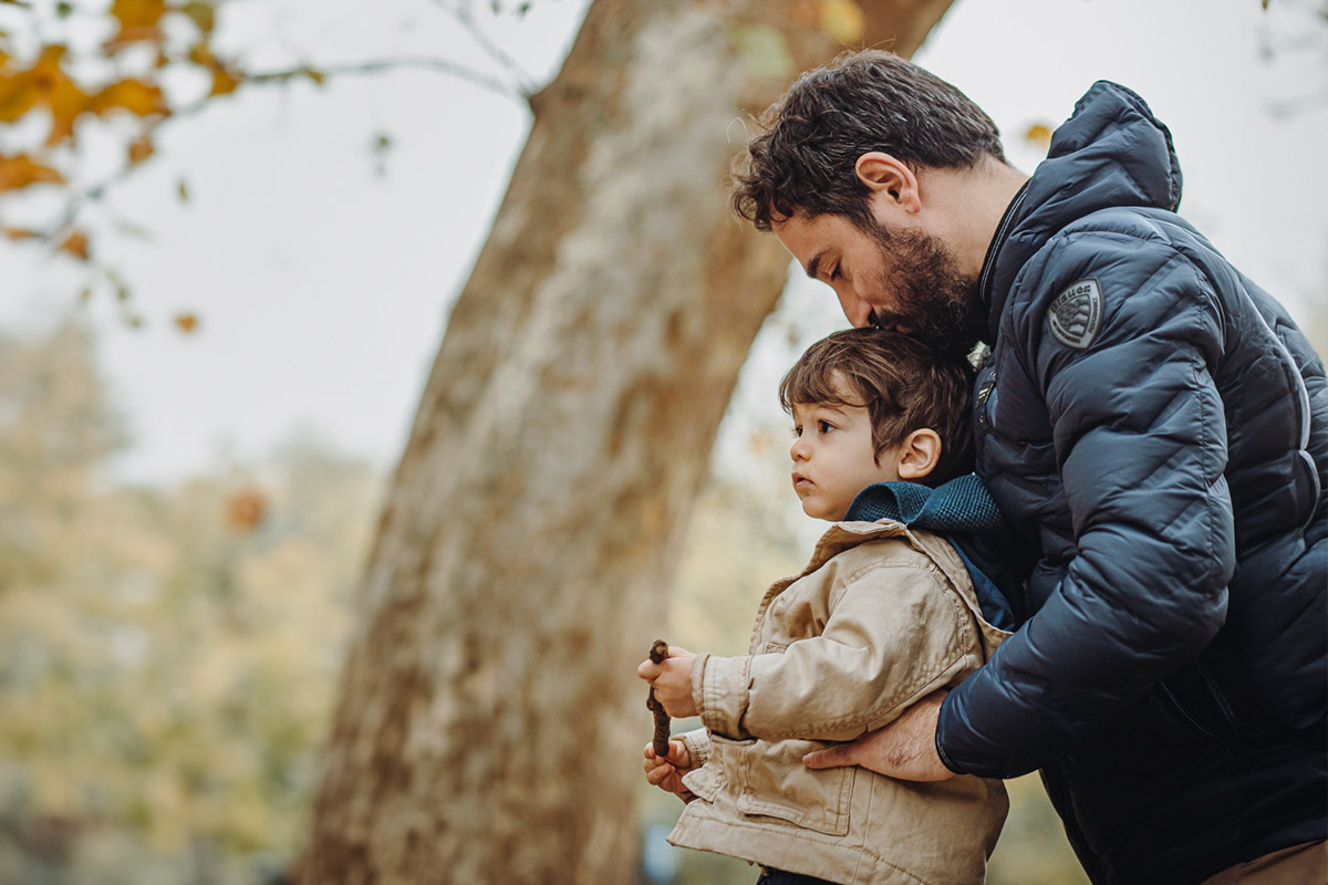 Parco del Valentino, fotografia di famiglia. Sessione fotografica autunnale. Papà bacia il bambino sulla testa.