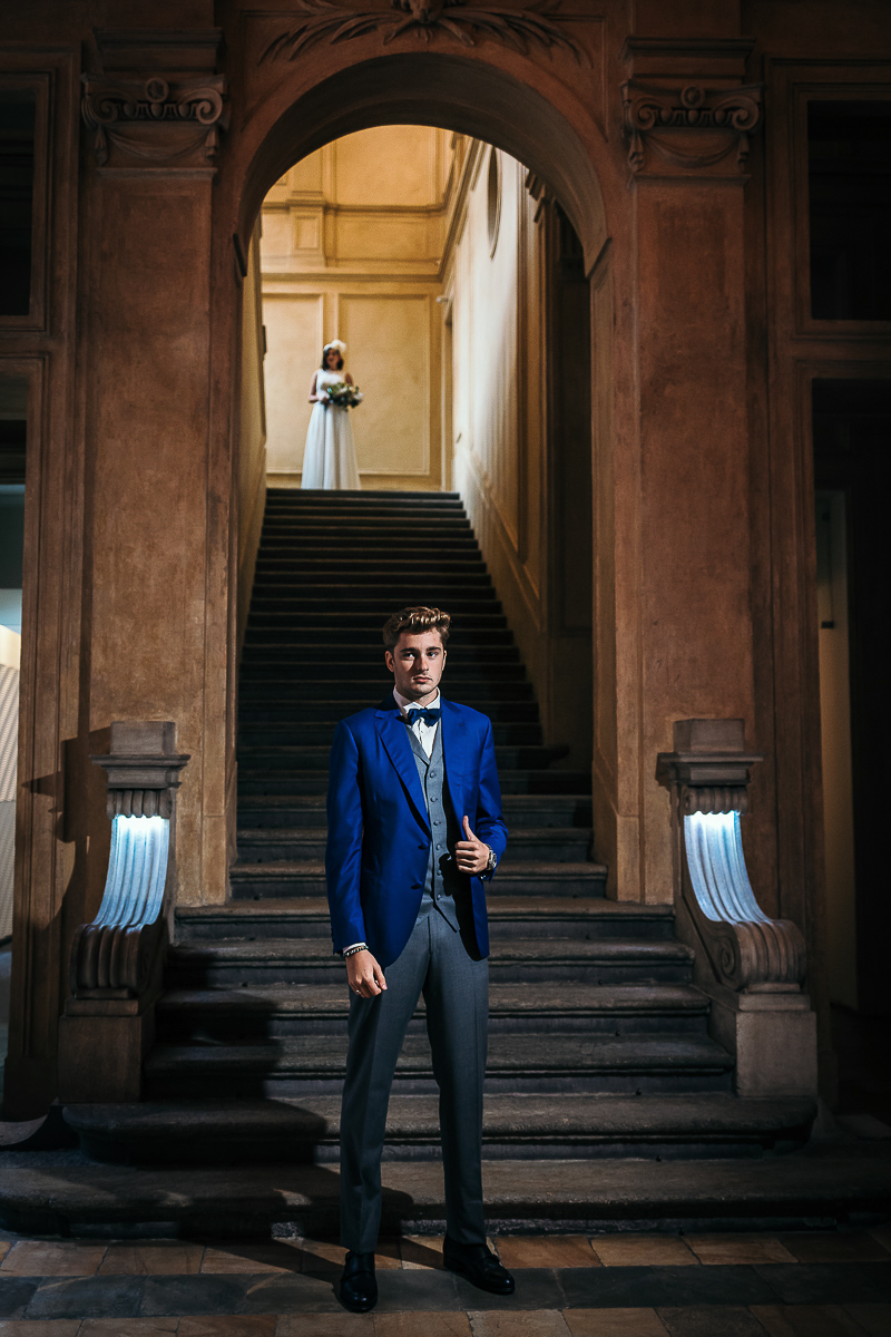 The number 6, Torino, editorial wedding. First look. Sposa che scende lo scalone alle spalle dello sposo.