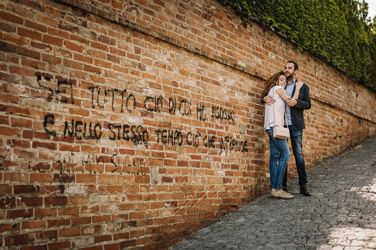 Prematrimoniale nel centro medievale di Chieri. Giulia e Domenico davanti ad un muro medievale con una scritta.