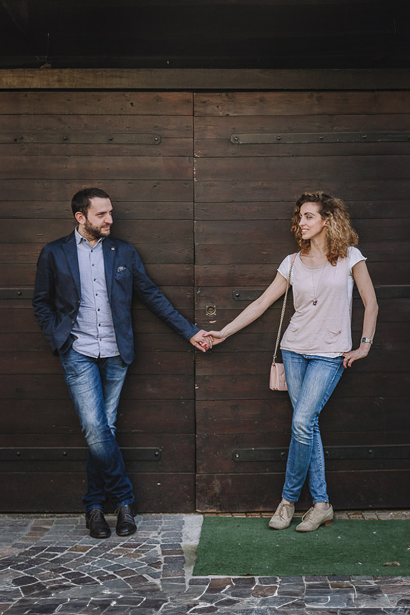 Prematrimoniale nel centro medievale di Chieri. Giulia e Domenico si danno la mano davanti ad un portone.
