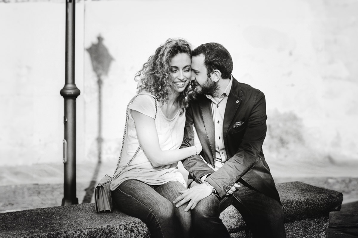 Prematrimoniale nel centro medievale di Chieri. Giulia e Domenico seduti su di una panchina. Bianco e nero.