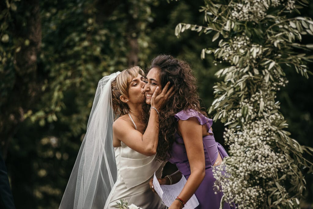 Matrimonio shabby chic a Villa Delfini di Morsasco in Monferrato.Cerimonia all'aperto. Bacio della sposa alla damigella d'onore.