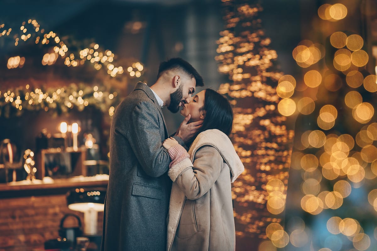 Servizio fotografico di coppia natalizio nel centro di Torino. Coppia davanti alla Rinascente con gli alberi e le luci di Natale.