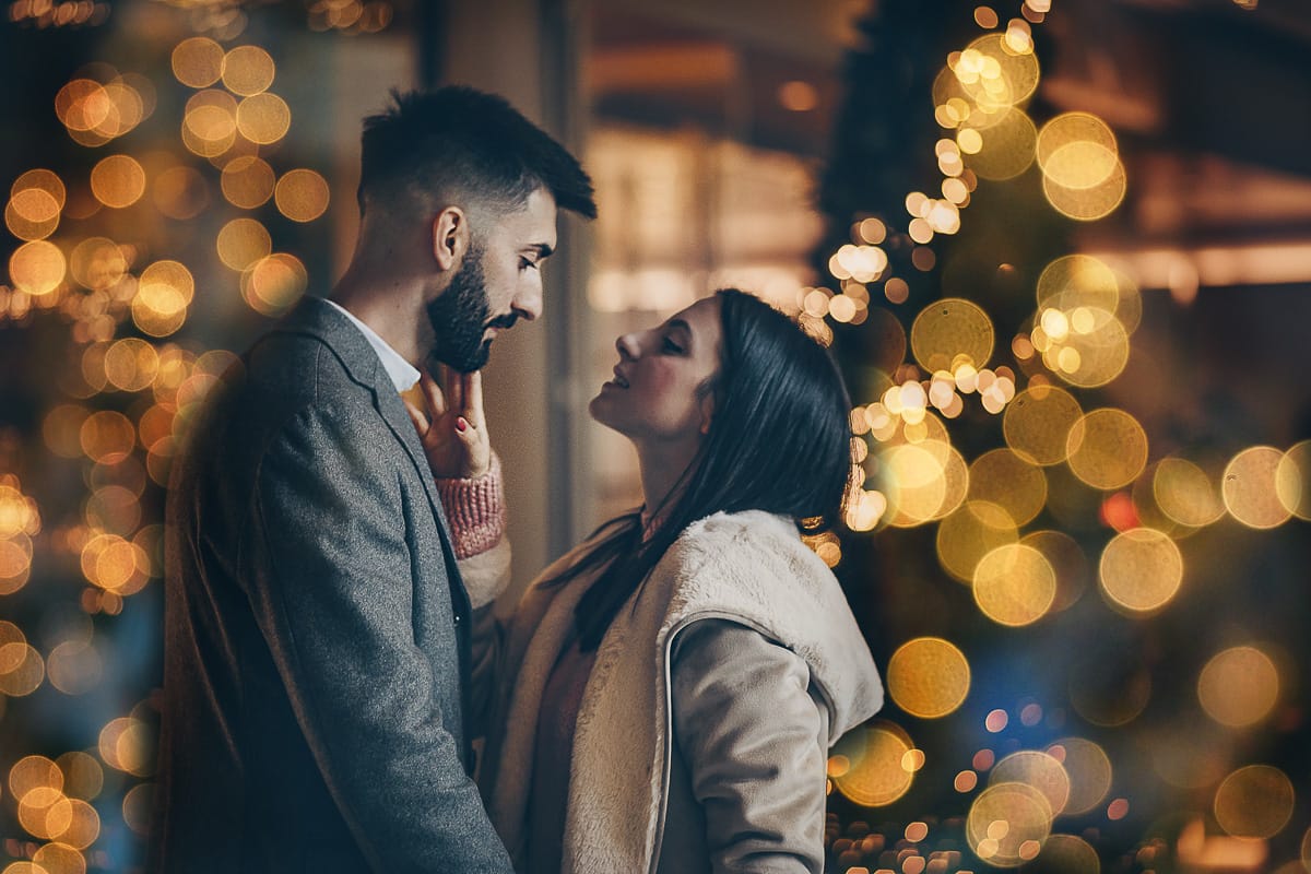 Servizio fotografico di coppia natalizio nel centro di Torino. Coppia davanti alla Rinascente con gli alberi e le luci di Natale.Bokeh