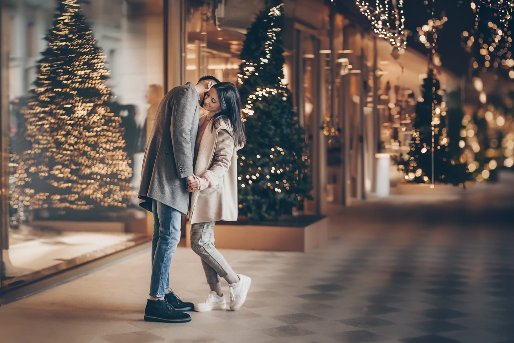 Servizio fotografico di coppia natalizio nel centro di Torino. Coppia davanti alla Rinascente con gli alberi e le luci di Natale.