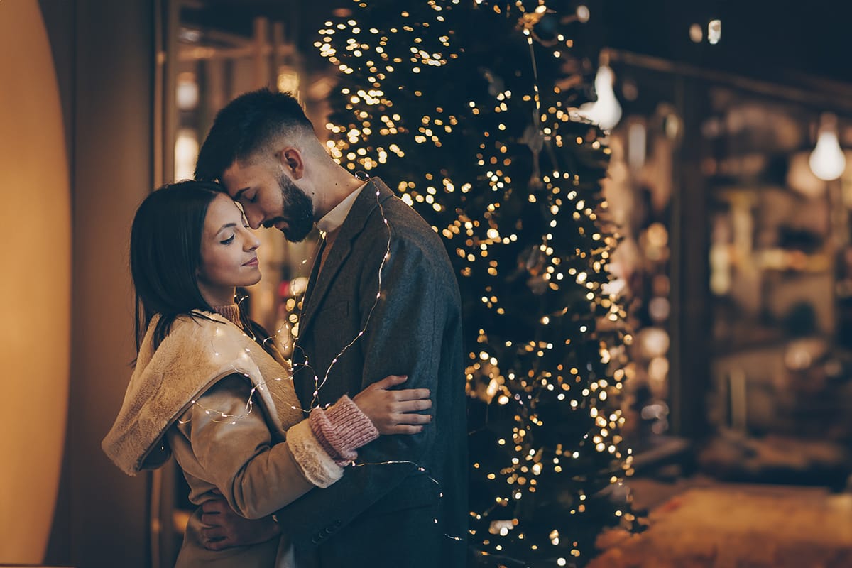 Servizio fotografico di coppia natalizio nel centro di Torino. Coppia davanti alla Rinascente con gli alberi e le luci di Natale.