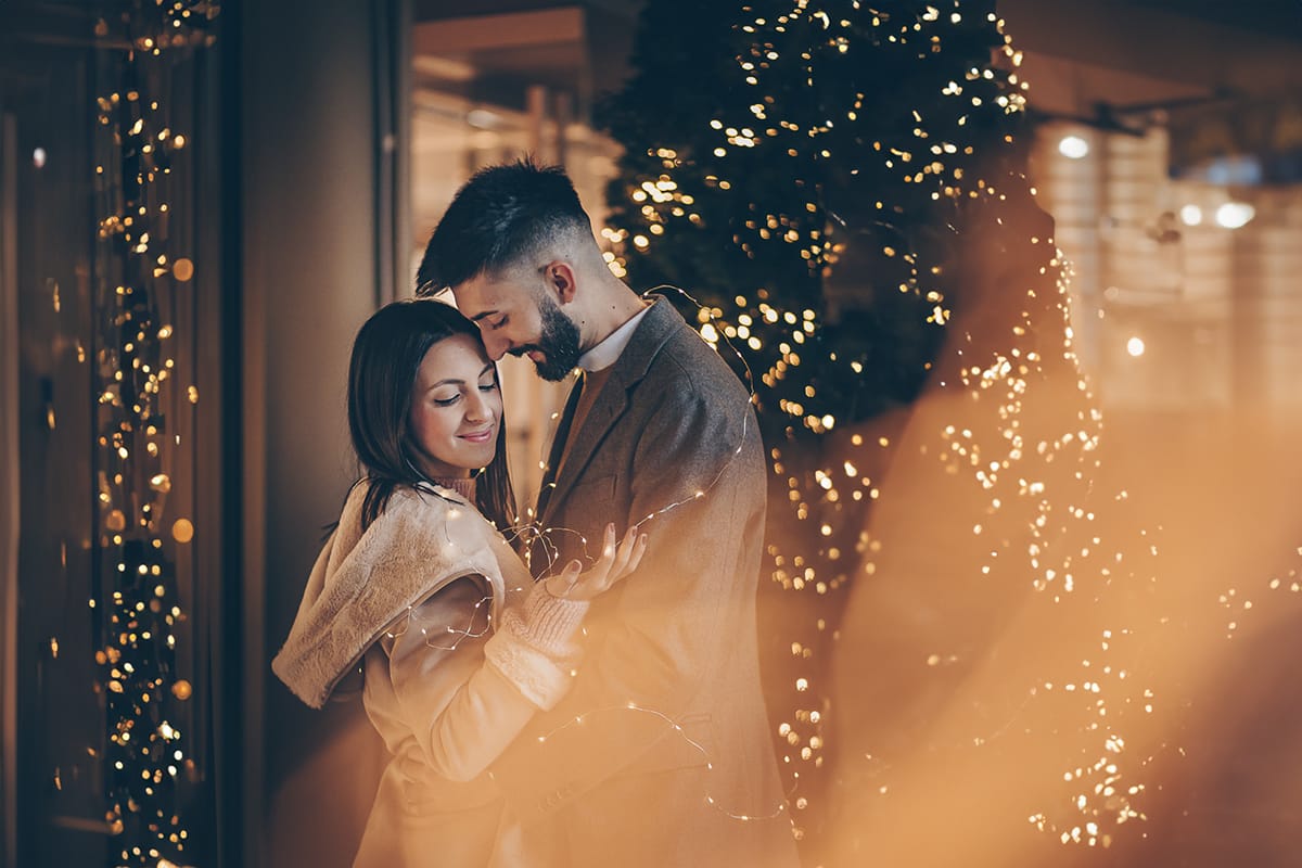 Servizio fotografico di coppia natalizio nel centro di Torino. Coppia davanti alla Rinascente con gli alberi e le luci di Natale.