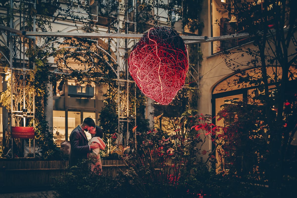 Servizio fotografico di coppia natalizio nel centro di Torino. Coppia nel cortile della Boutique San Carlo dal 1973.