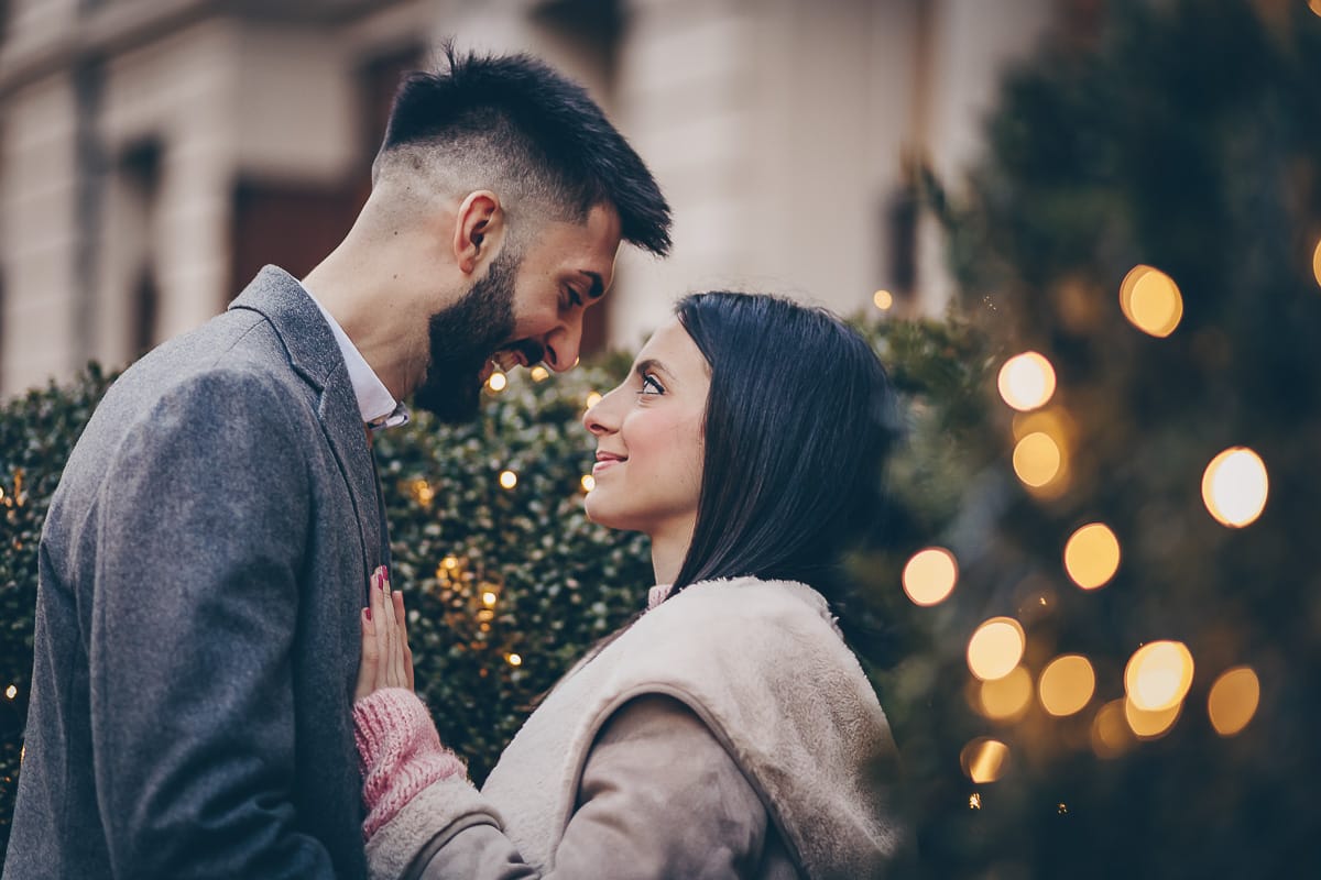 Servizio fotografico di coppia natalizio nel centro di Torino. Coppia in piazza Carignano con le luci natalizie che creano il bokeh.