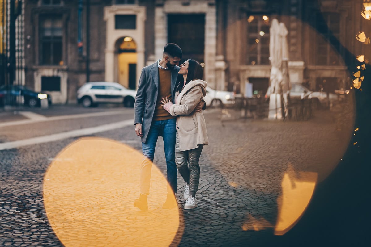 Servizio fotografico di coppia natalizio nel centro di Torino. Coppia in piazza Carignano con le luci natalizie che creano il bokeh.