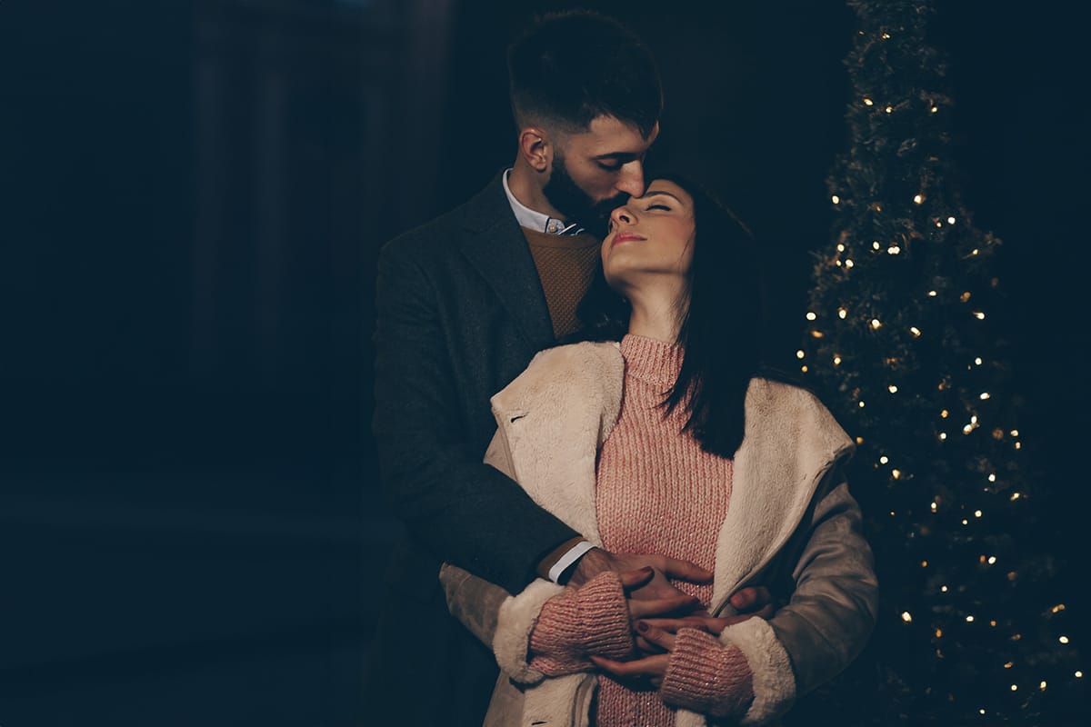Servizio fotografico di coppia natalizio nel centro di Torino. Coppia in piazza Carignano nell'androne di un palazzo addobbato per Natale. bacio. Flash esterno davanti la coppia.