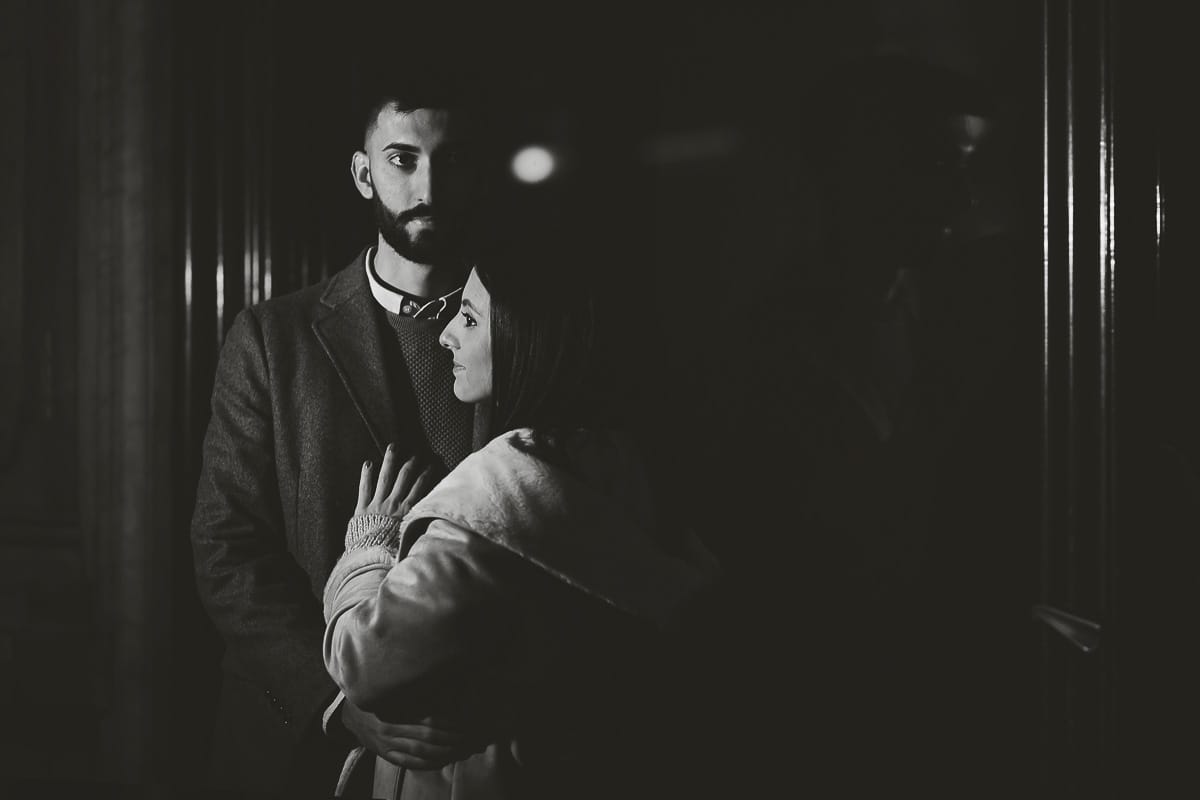 Servizio fotografico di coppia natalizio nel centro di Torino. Coppia in piazza Carignano nell'androne di un palazzo addobbato per Natale. bacio. Flash esterno sulla coppia.