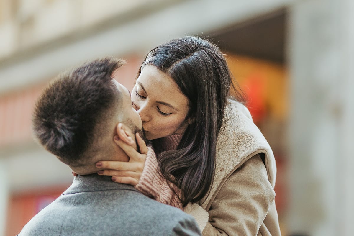 Servizio fotografico di coppia natalizio nel centro di Torino. Coppia nella via davanti alla Rinascente. Bacio.