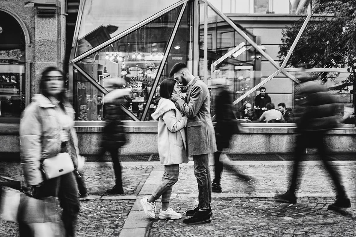 Servizio fotografico di coppia natalizio nel centro di Torino. Coppia nella via davanti alla Rinascente. Mosso creativo. Bianco e nero.