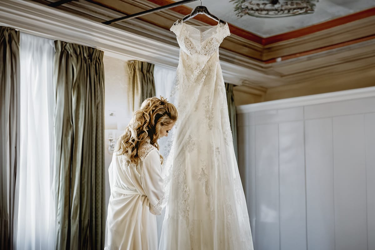 Destination wedding al Relais Sant'Uffizio. Preparazione della sposa. Sposa con il suo abito da sposa appeso.